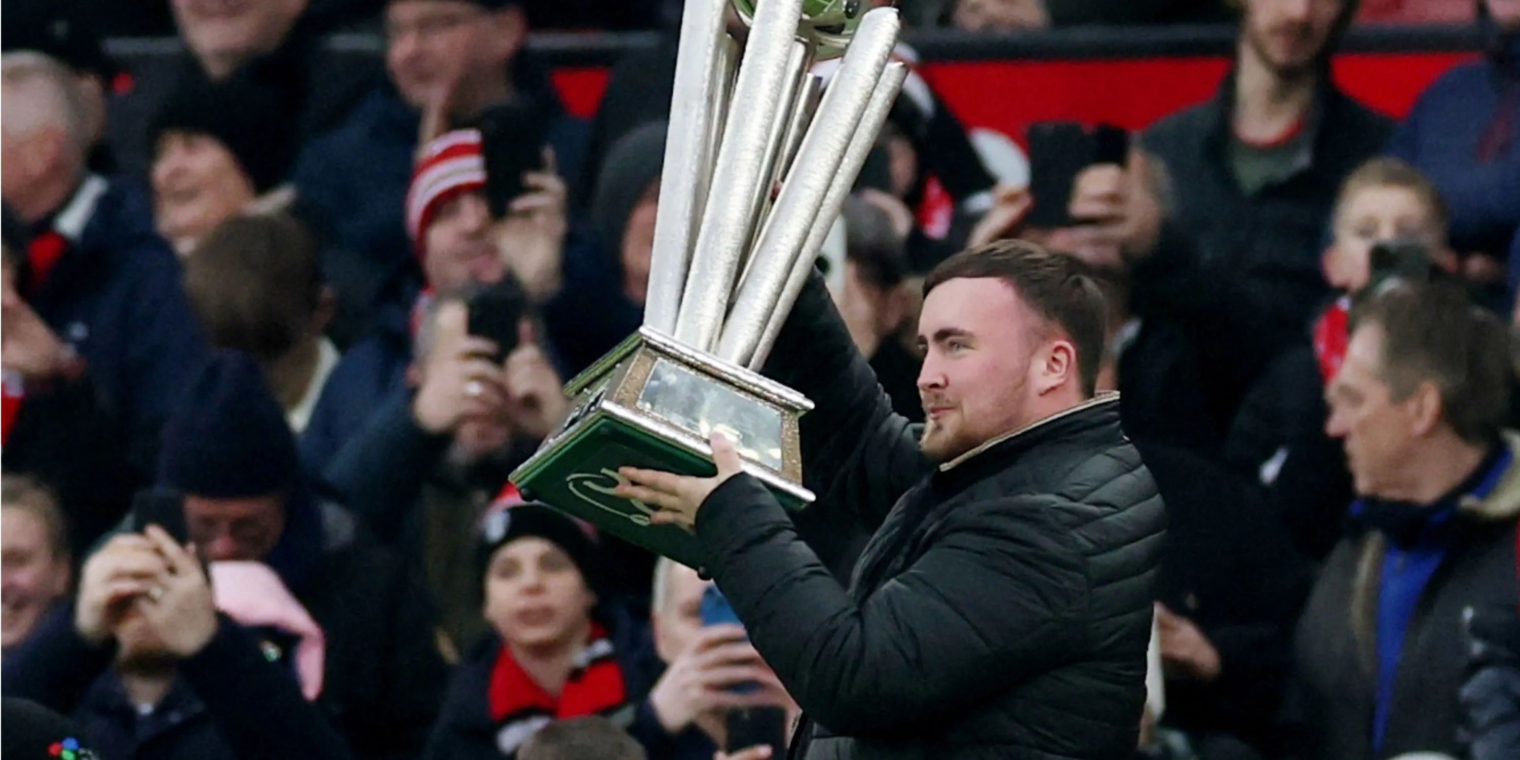 Thần đồng phi tiêu Luke Littler với chiếc cúp vô địch thế giới tại sân Old Trafford, thể hiện sự hâm mộ Manchester United.